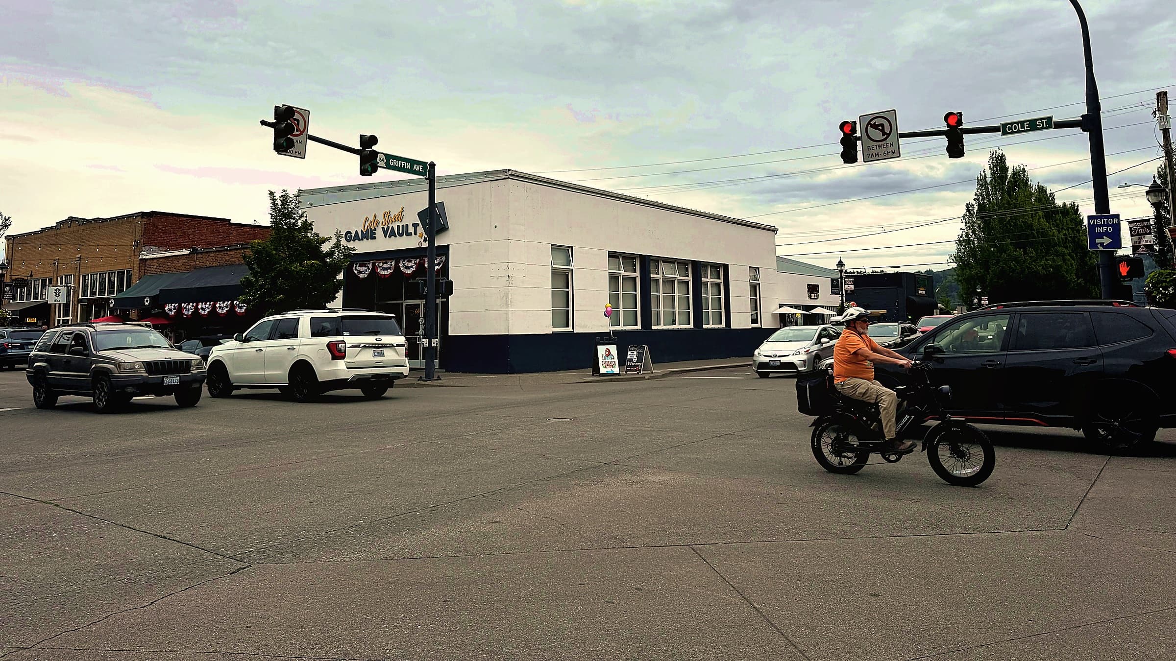 The traffic signal at Cole Street and Griffin Avenue in downtown Enumclaw on an overcast day, with cars and a cyclist crossing