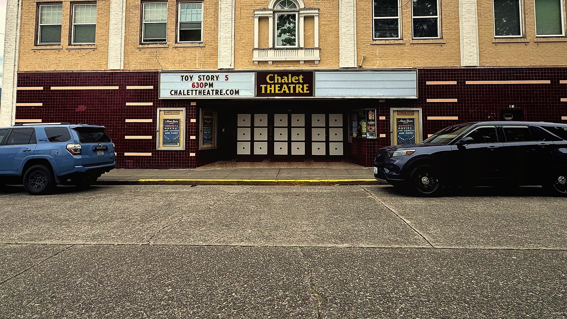 The Chalet Theatre on Wells Street in Enumclaw: brick upper storey, maroon tile band, marquee and white porthole doors